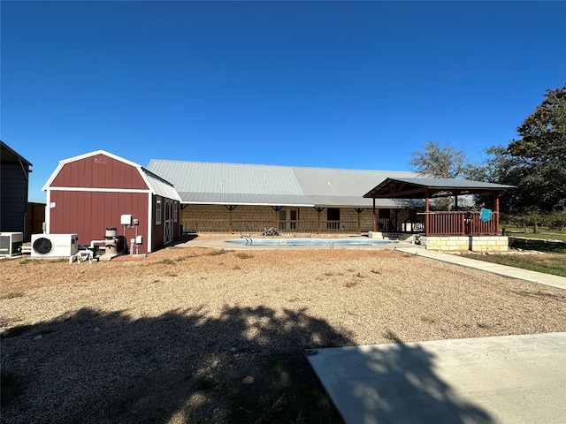 exterior space with central air condition unit, an outdoor structure, and a fenced in pool