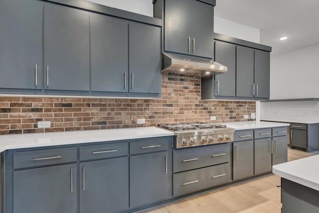 kitchen with gray cabinets, backsplash, stainless steel gas stovetop, and light wood-type flooring