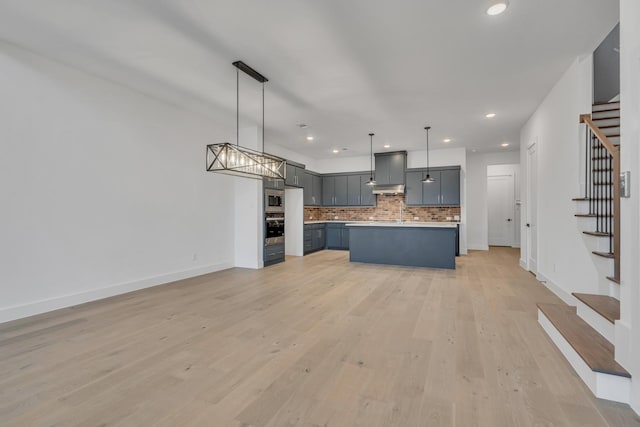 kitchen featuring a center island, decorative backsplash, light wood-type flooring, pendant lighting, and stainless steel appliances