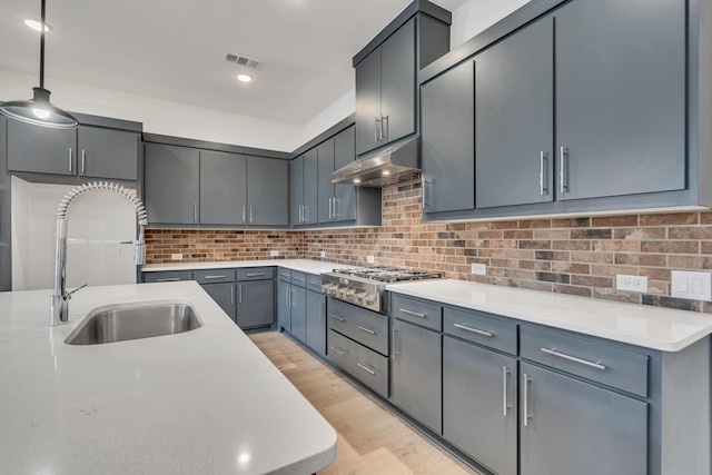 kitchen with pendant lighting, sink, tasteful backsplash, gray cabinetry, and stainless steel gas cooktop