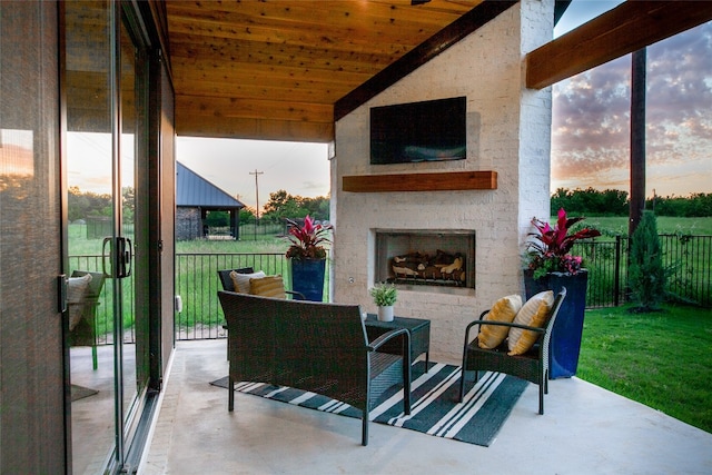 patio terrace at dusk with a large fireplace and a yard