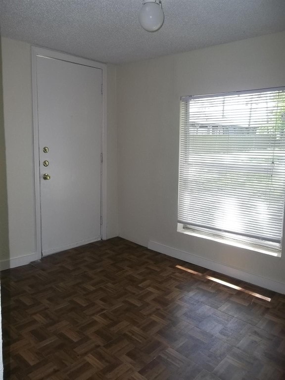 unfurnished room featuring a textured ceiling and dark parquet flooring