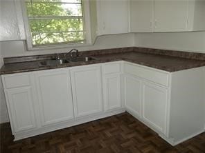 kitchen with white cabinets and dark parquet flooring