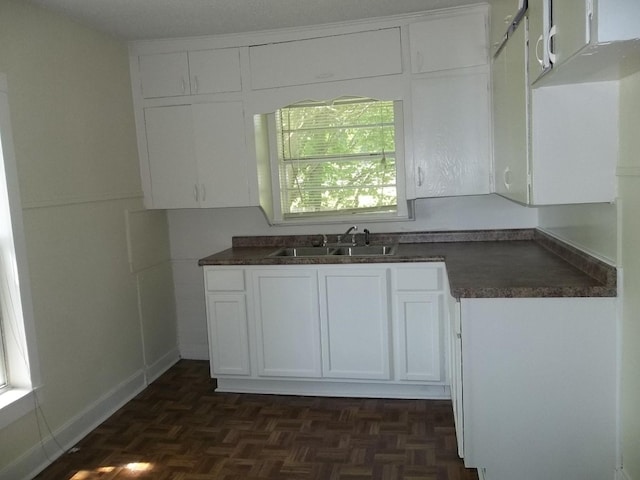 kitchen with white cabinets, dark parquet floors, and sink