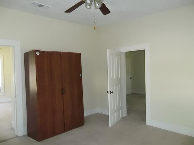 unfurnished bedroom featuring ceiling fan, a closet, and light colored carpet