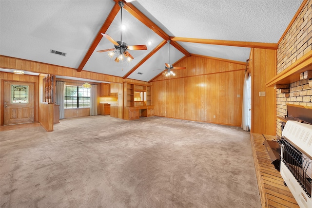 unfurnished living room with wooden walls, ceiling fan, heating unit, vaulted ceiling with beams, and light colored carpet