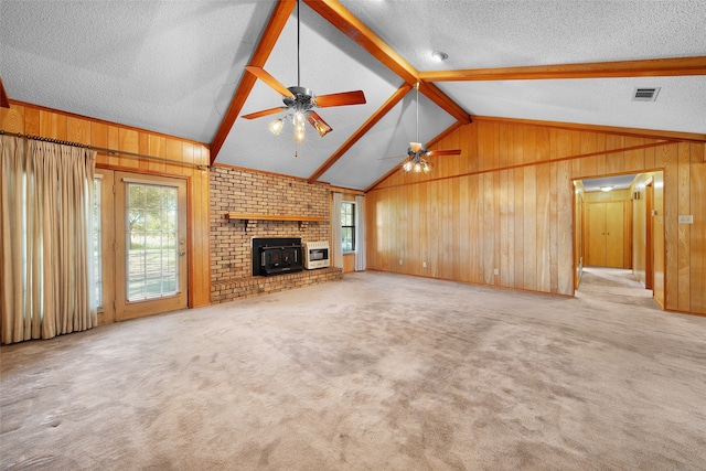 unfurnished living room with a textured ceiling, ceiling fan, wooden walls, and light carpet