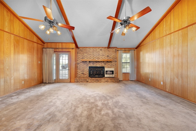 unfurnished living room with light carpet, wooden walls, ceiling fan, and a textured ceiling