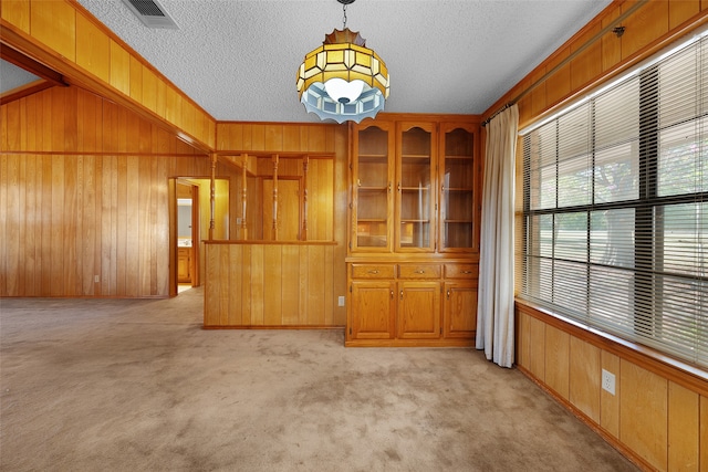 unfurnished room with wood walls, light colored carpet, and a textured ceiling