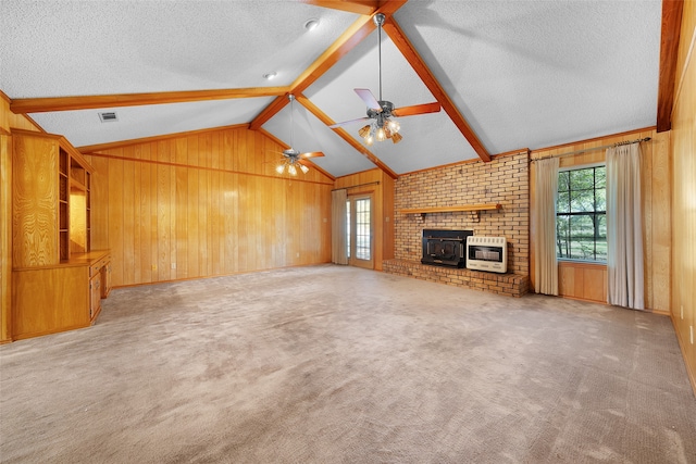 unfurnished living room with wood walls, ceiling fan, light colored carpet, heating unit, and a wood stove