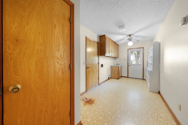 laundry area with ceiling fan, cabinets, and a textured ceiling