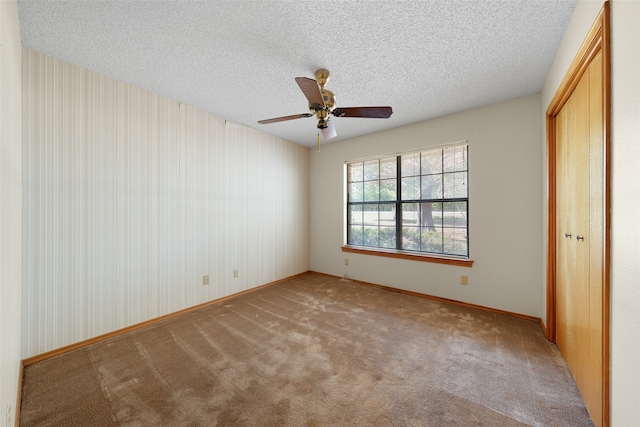 unfurnished bedroom with ceiling fan, a textured ceiling, and light carpet