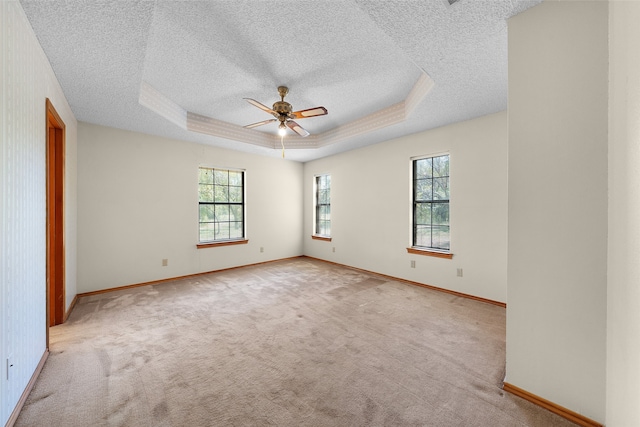 carpeted spare room featuring ceiling fan, a tray ceiling, and a textured ceiling