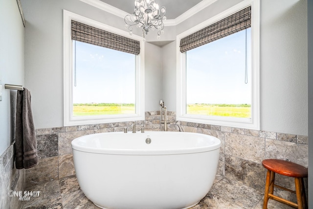 bathroom featuring a wainscoted wall, ornamental molding, an inviting chandelier, a soaking tub, and tile walls