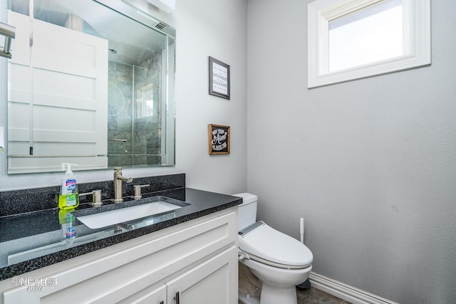 bathroom featuring vanity, toilet, baseboards, and a shower with shower door