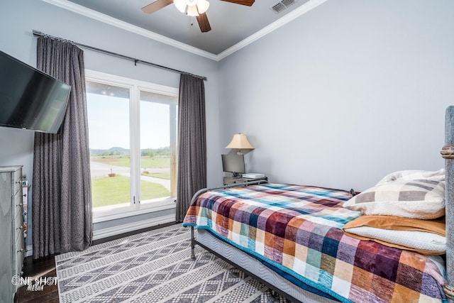 bedroom with a ceiling fan, wood finished floors, visible vents, baseboards, and crown molding