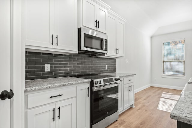 kitchen with light hardwood / wood-style flooring, light stone countertops, tasteful backsplash, white cabinetry, and stainless steel appliances