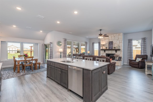 kitchen with dishwasher, light wood-style flooring, light countertops, a fireplace, and a sink