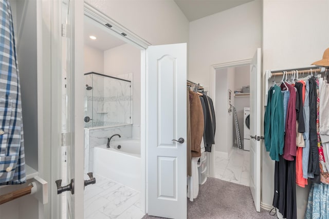 bathroom featuring marble finish floor, a bath, washer / clothes dryer, a stall shower, and a walk in closet