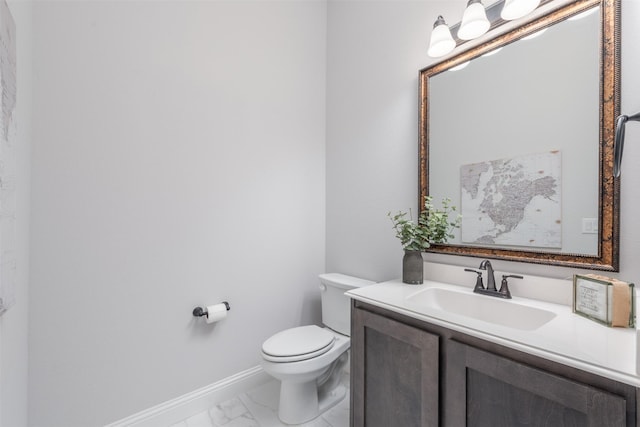 half bath featuring marble finish floor, toilet, vanity, and baseboards