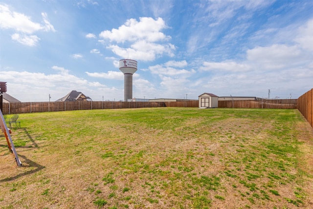 view of yard featuring a fenced backyard, a storage unit, and an outdoor structure