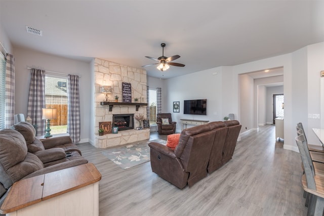 living room with hardwood / wood-style flooring, ceiling fan, a healthy amount of sunlight, and a stone fireplace