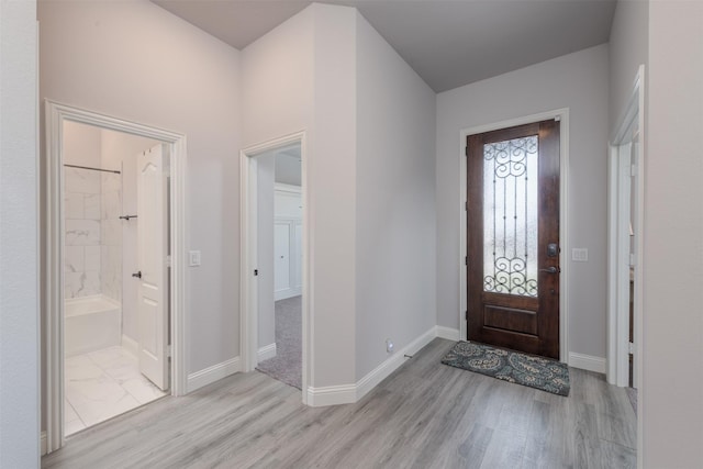 foyer entrance with light wood-style floors and baseboards