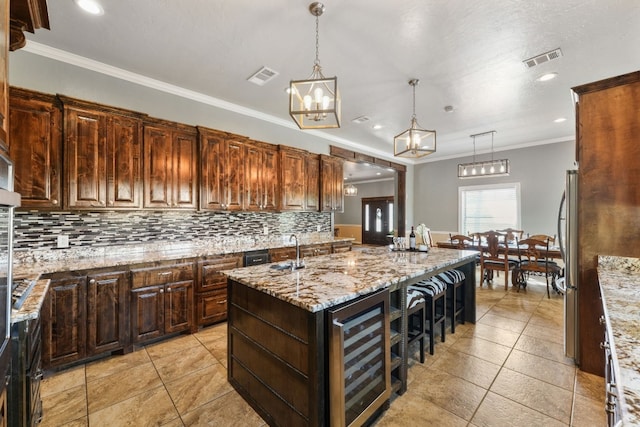 kitchen with backsplash, a center island with sink, wine cooler, and pendant lighting