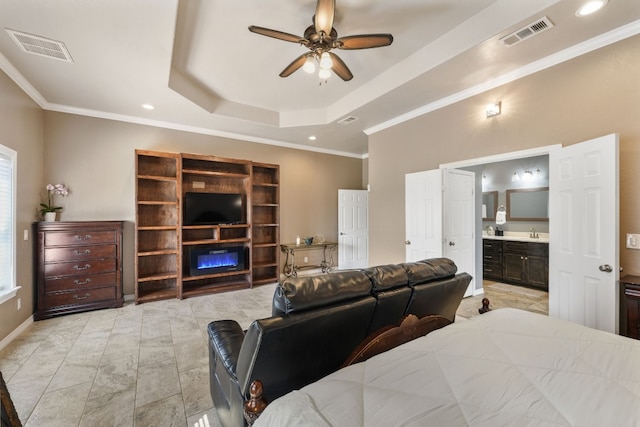 tiled bedroom with ensuite bath, ornamental molding, ceiling fan, and a tray ceiling