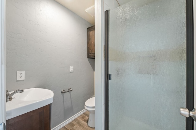 bathroom with toilet, vanity, hardwood / wood-style flooring, and a shower with shower door