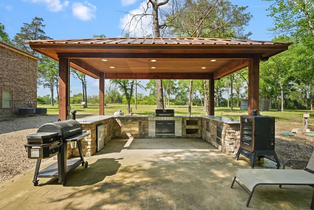 view of terrace featuring exterior kitchen, a gazebo, and a grill