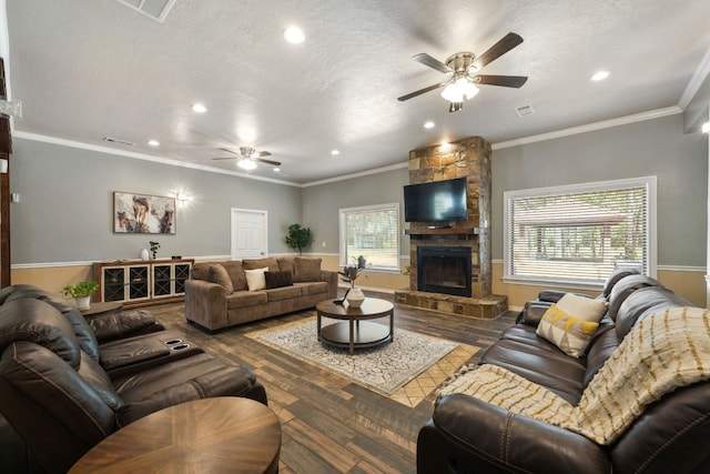 living room with ceiling fan, a textured ceiling, a stone fireplace, and dark hardwood / wood-style flooring