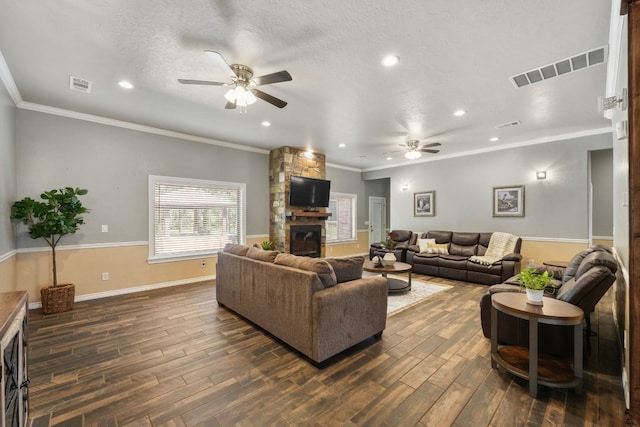 living room featuring dark wood-type flooring, a fireplace, ceiling fan, a textured ceiling, and ornamental molding