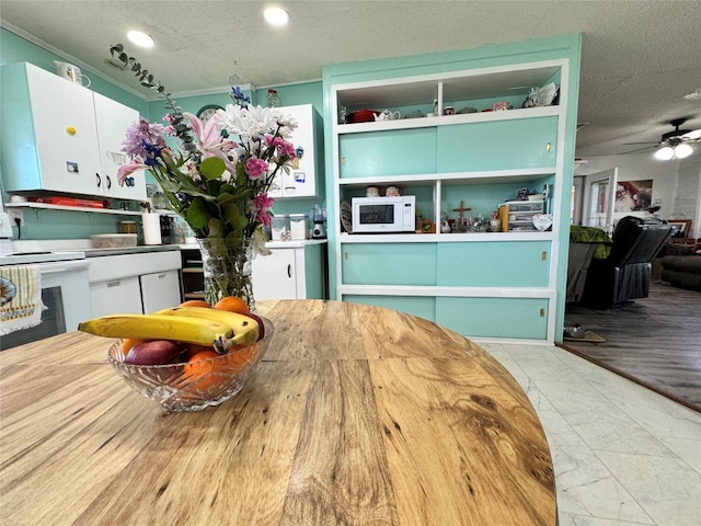 interior space featuring ceiling fan, white appliances, light tile floors, and white cabinets