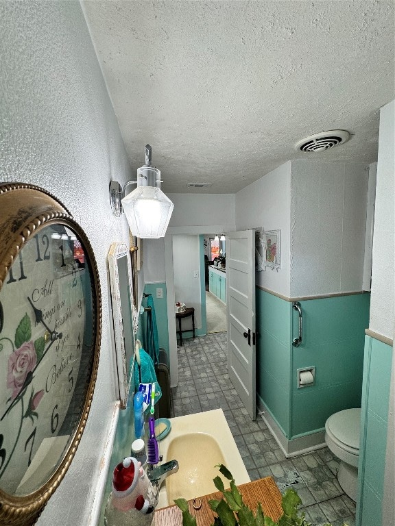 bathroom with a textured ceiling, vanity, toilet, and tile floors