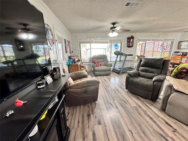 living room featuring ceiling fan, ornamental molding, light hardwood / wood-style flooring, and a textured ceiling