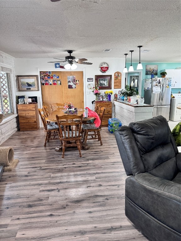 dining space featuring ceiling fan, a textured ceiling, and light hardwood / wood-style flooring