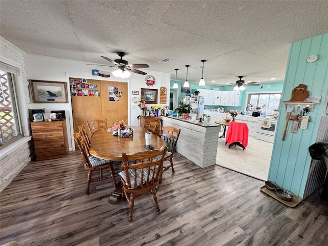 dining space with a textured ceiling, ceiling fan, and dark hardwood / wood-style floors