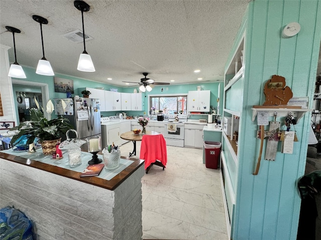 kitchen with decorative light fixtures, ceiling fan, stainless steel refrigerator, and white cabinetry