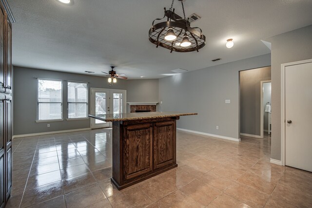 unfurnished living room featuring ceiling fan, light tile patterned floors, a tile fireplace, and french doors