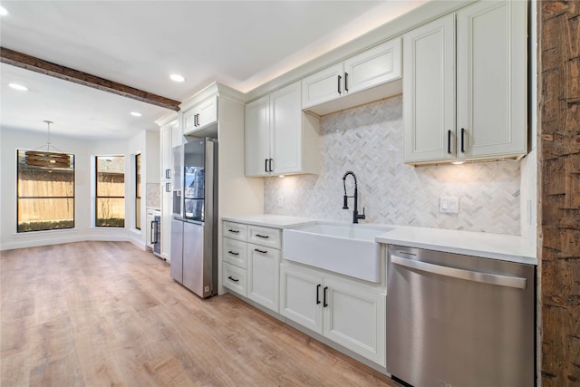 kitchen featuring stainless steel appliances, sink, light wood-type flooring, pendant lighting, and beam ceiling