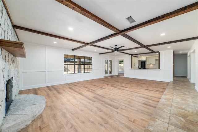 living room with beamed ceiling, ceiling fan, light wood-type flooring, coffered ceiling, and a stone fireplace