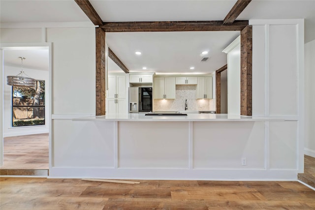 kitchen with beam ceiling, stainless steel fridge, light wood-type flooring, and decorative backsplash