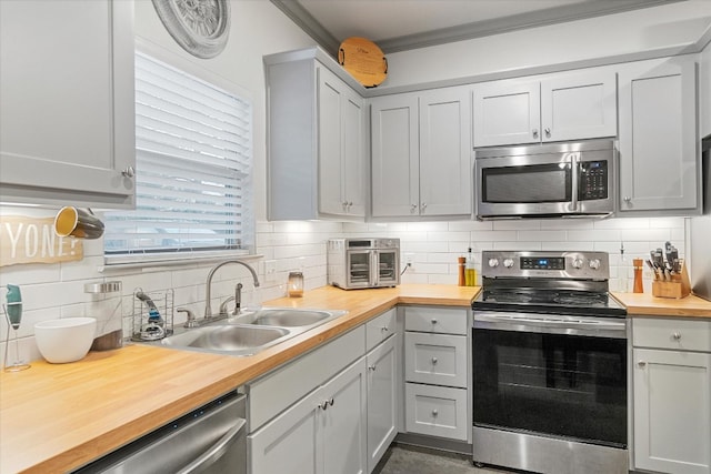 kitchen with backsplash, wood counters, stainless steel appliances, and sink