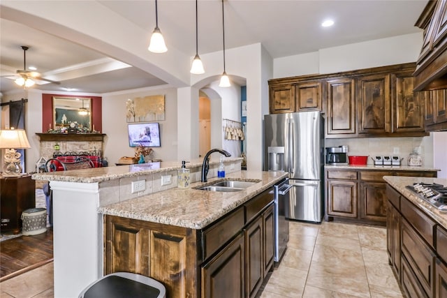 kitchen with a kitchen island with sink, ceiling fan, sink, tasteful backsplash, and decorative light fixtures