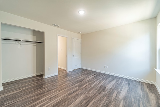 unfurnished bedroom with dark wood-type flooring and a closet