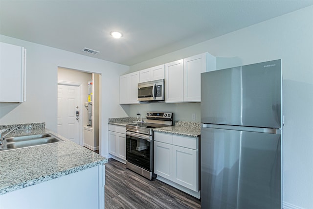 kitchen with white cabinetry, stainless steel appliances, sink, light stone counters, and dark wood-type flooring