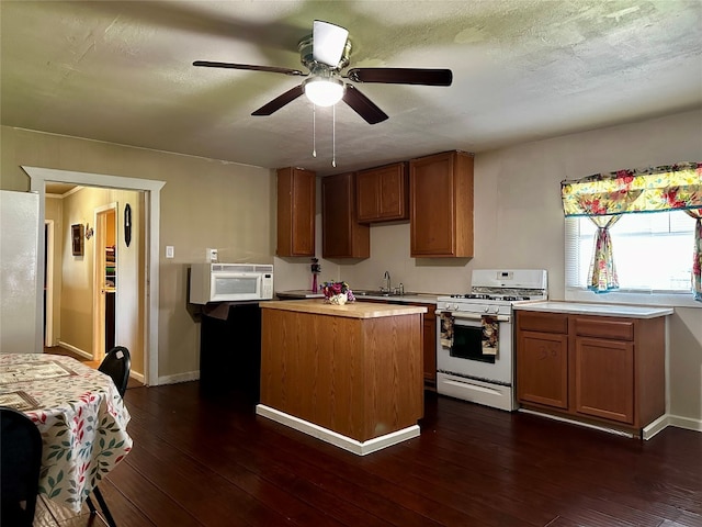 kitchen with dark hardwood / wood-style flooring, ceiling fan, white appliances, and a kitchen island