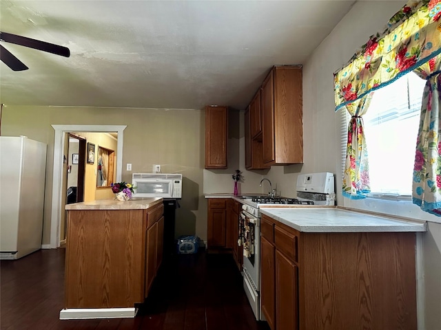 kitchen featuring white appliances, dark hardwood / wood-style floors, ceiling fan, and sink