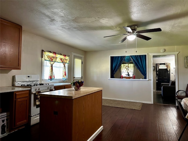 kitchen featuring dark wood-type flooring, white gas range, ceiling fan, and a textured ceiling